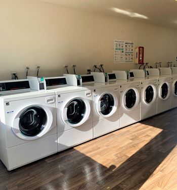 A row of white front load washing machines in a laundromat.